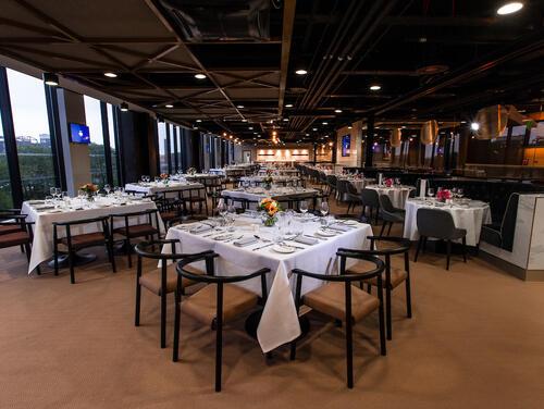 A venue et up for a dinner event with white table cloths and wooden tables/chairs