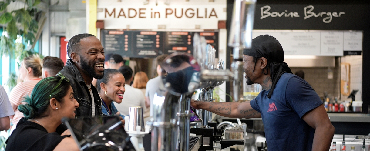 three people are being served drinks at the bar at Hackney Bridge