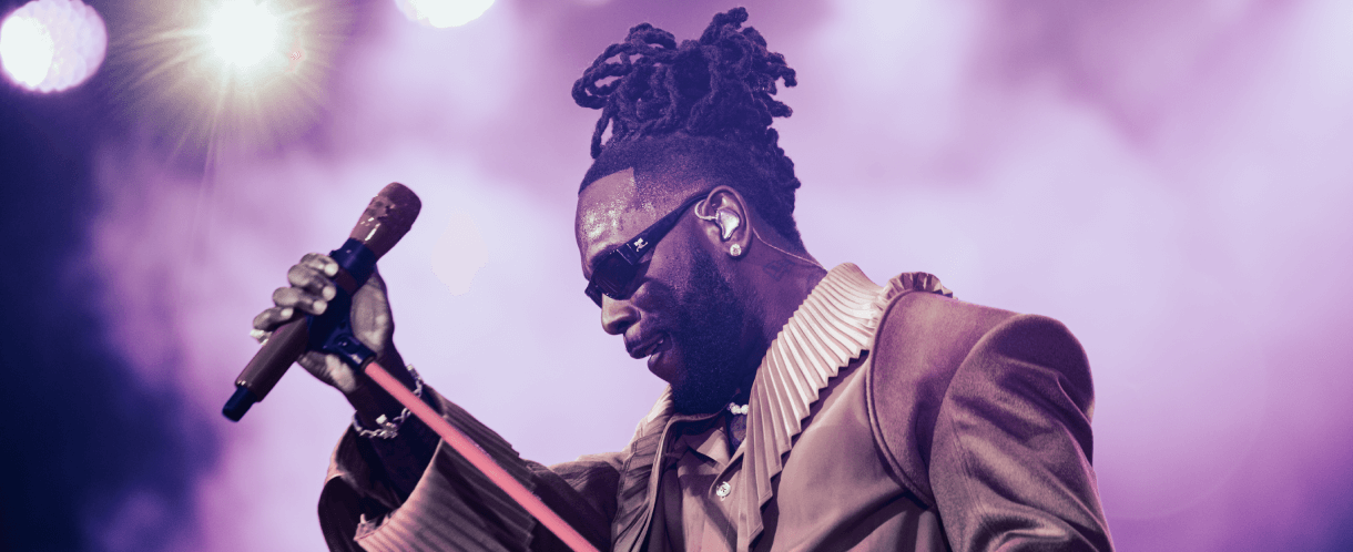 Burna Boy holds his up his mic on stage