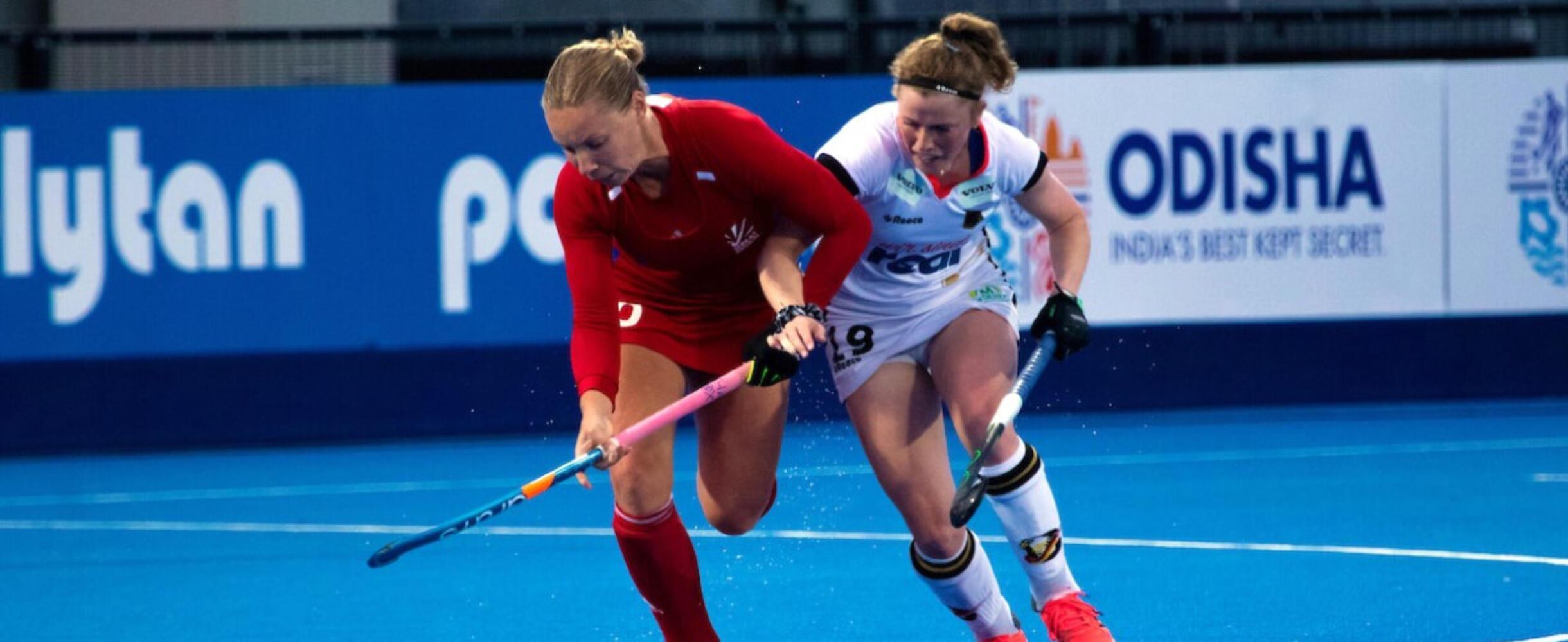 Two hockey players jostle for control of the ball