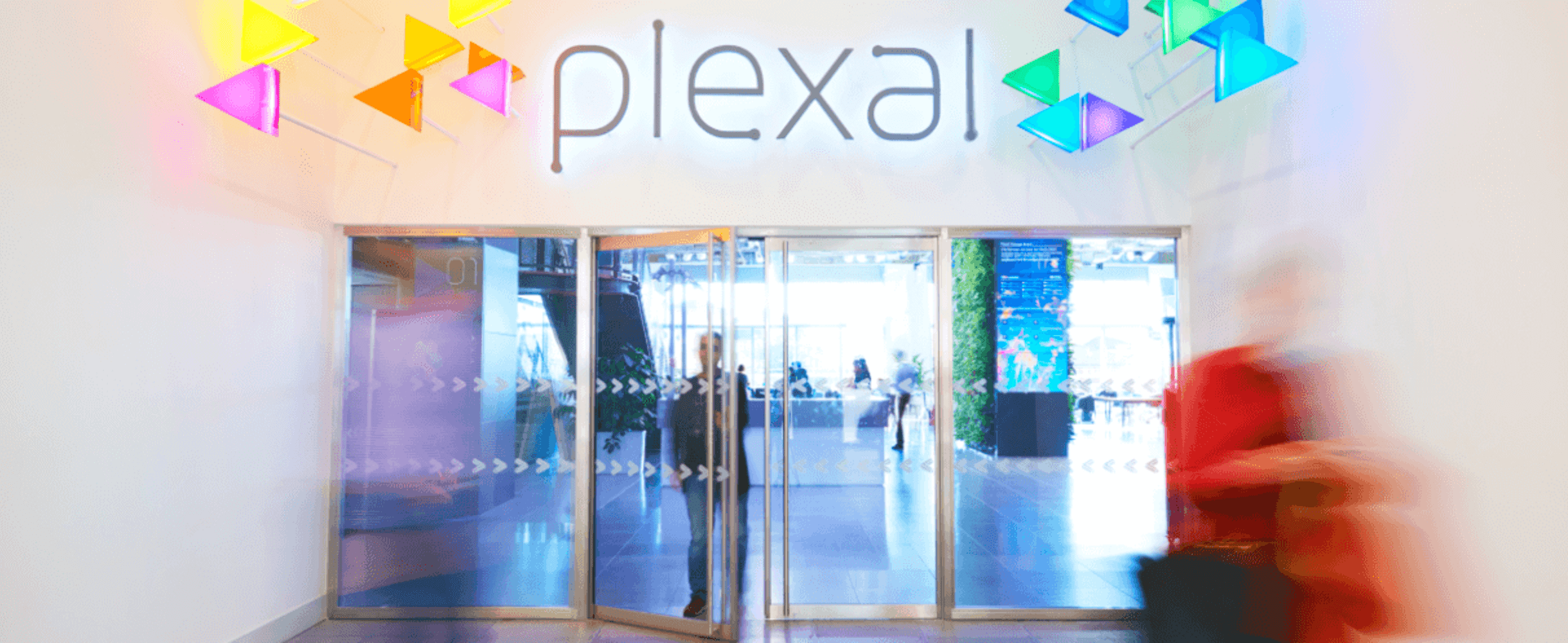 A blur of people walking through the colourful Plexal entrance