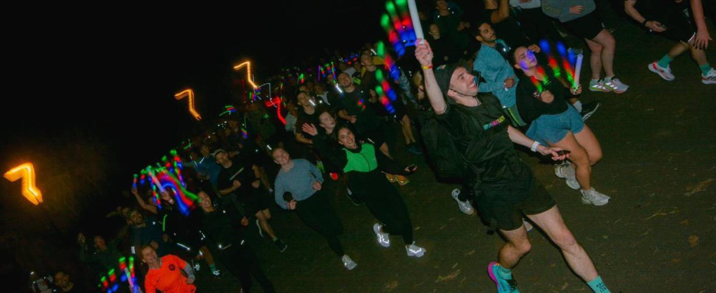 a group of runners with lights running in the dark