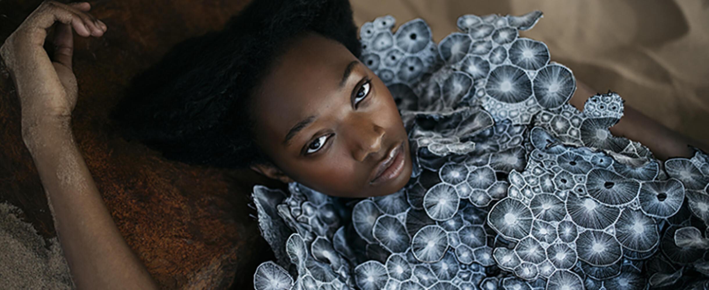 A person lies back in a designed outfit