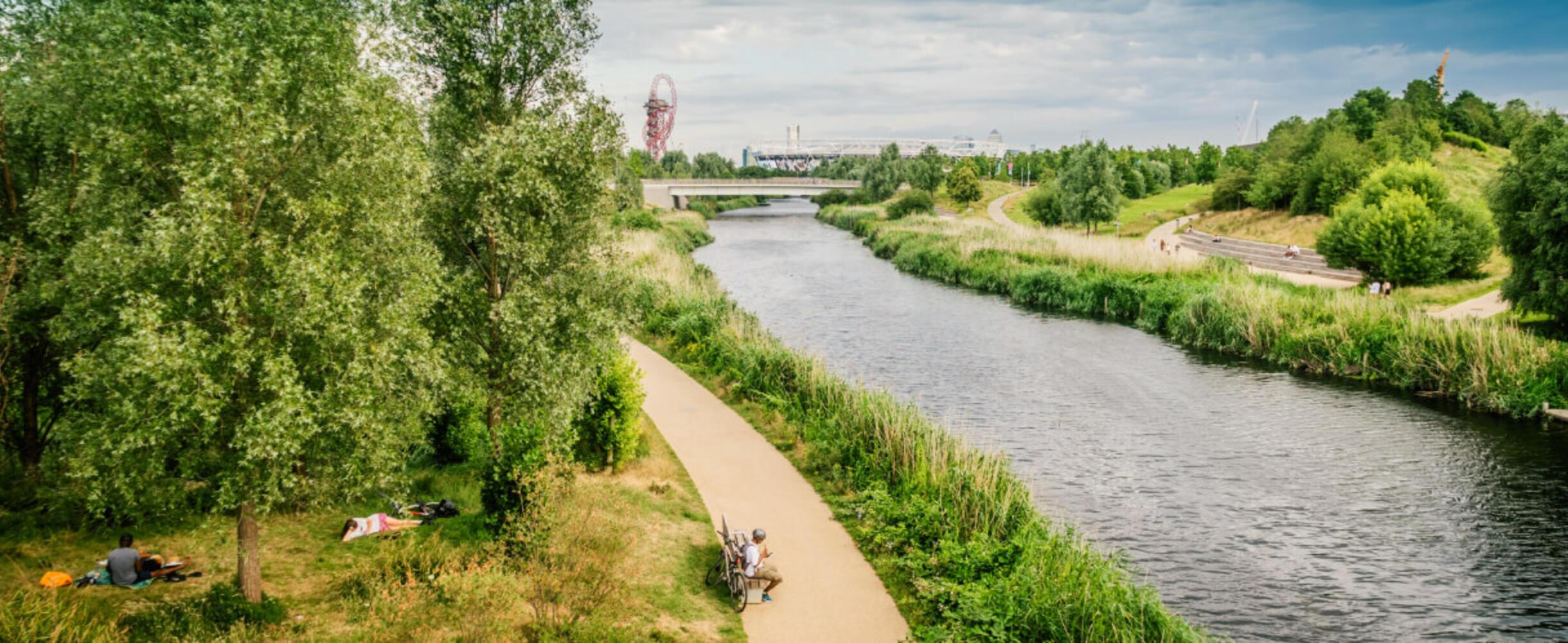 people sat by the river with ArcelorMittal Orbit in the background