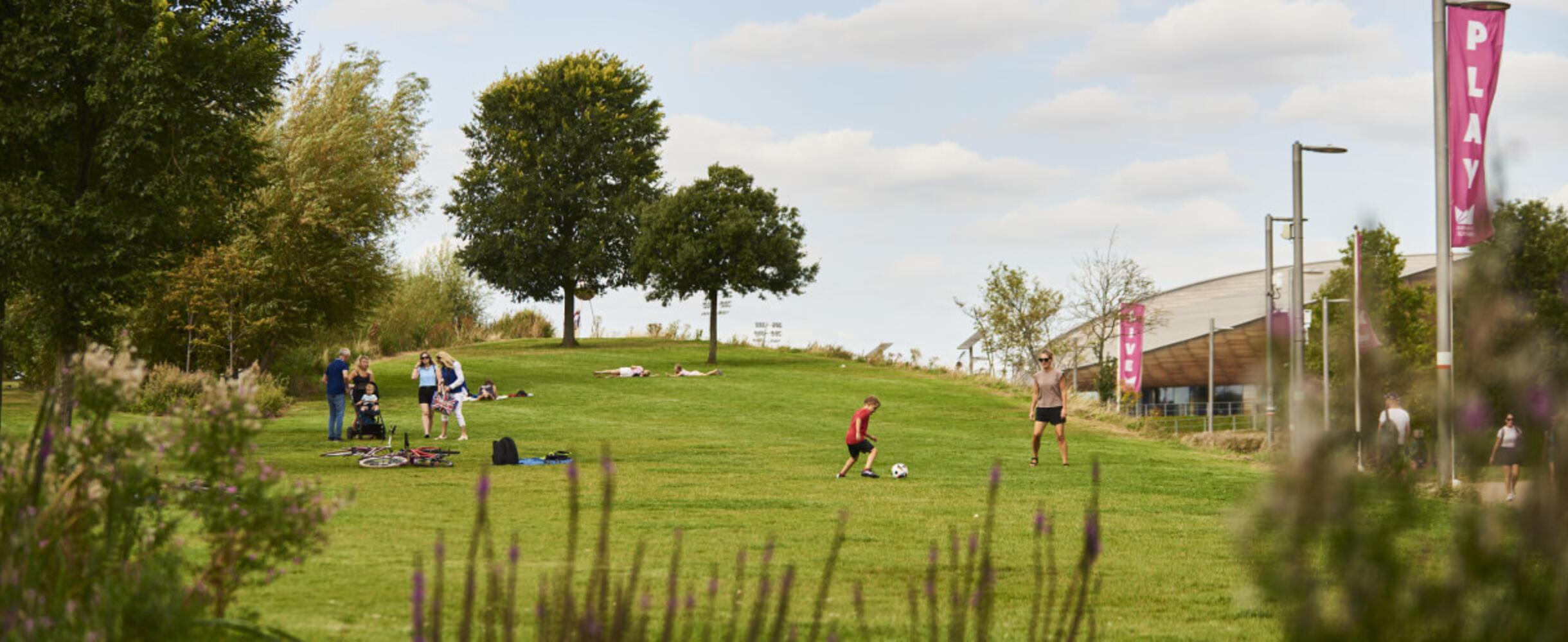 People lie or play in the sun at Queen Elizabeth Olympic Park