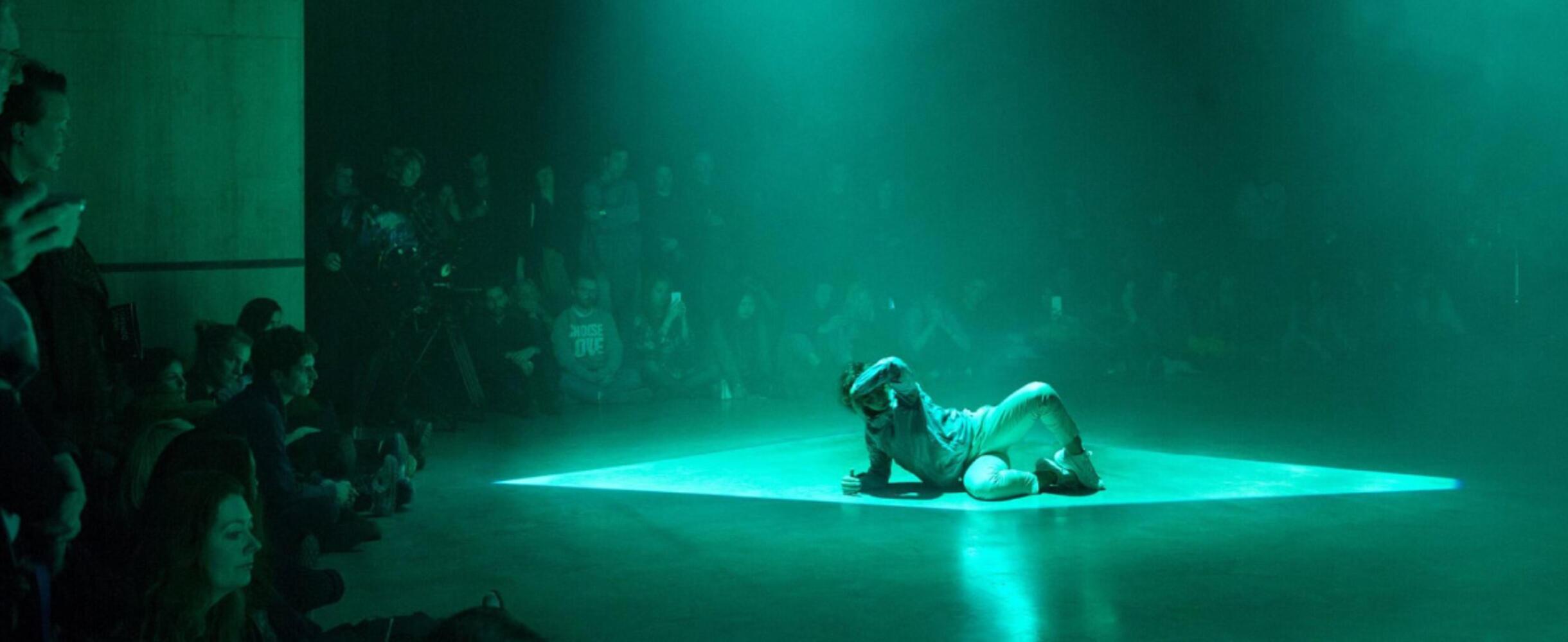 A dancer on stage with a light shining down on them