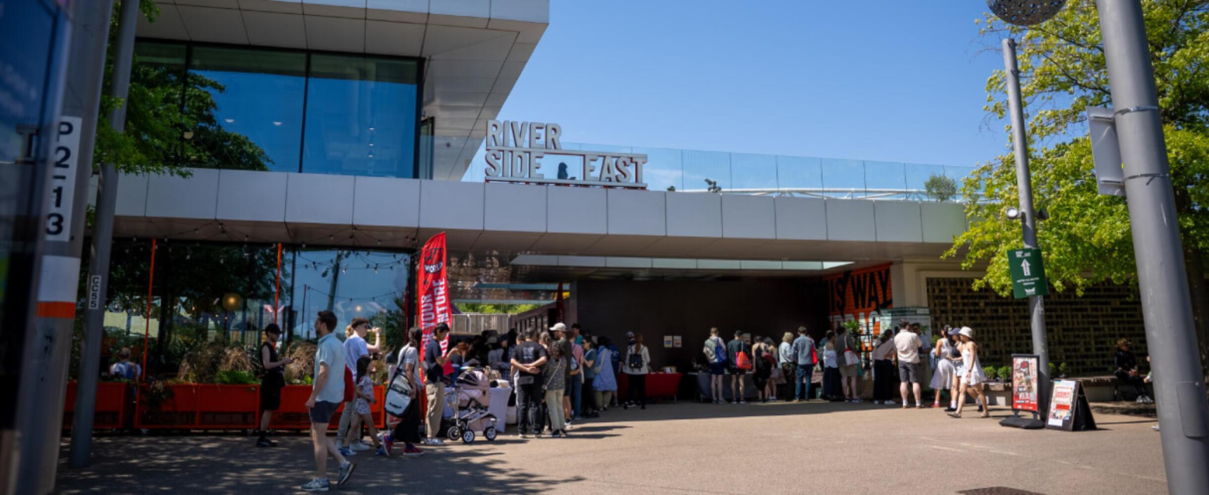 A crowd of people outside Riverside East on a sunny day