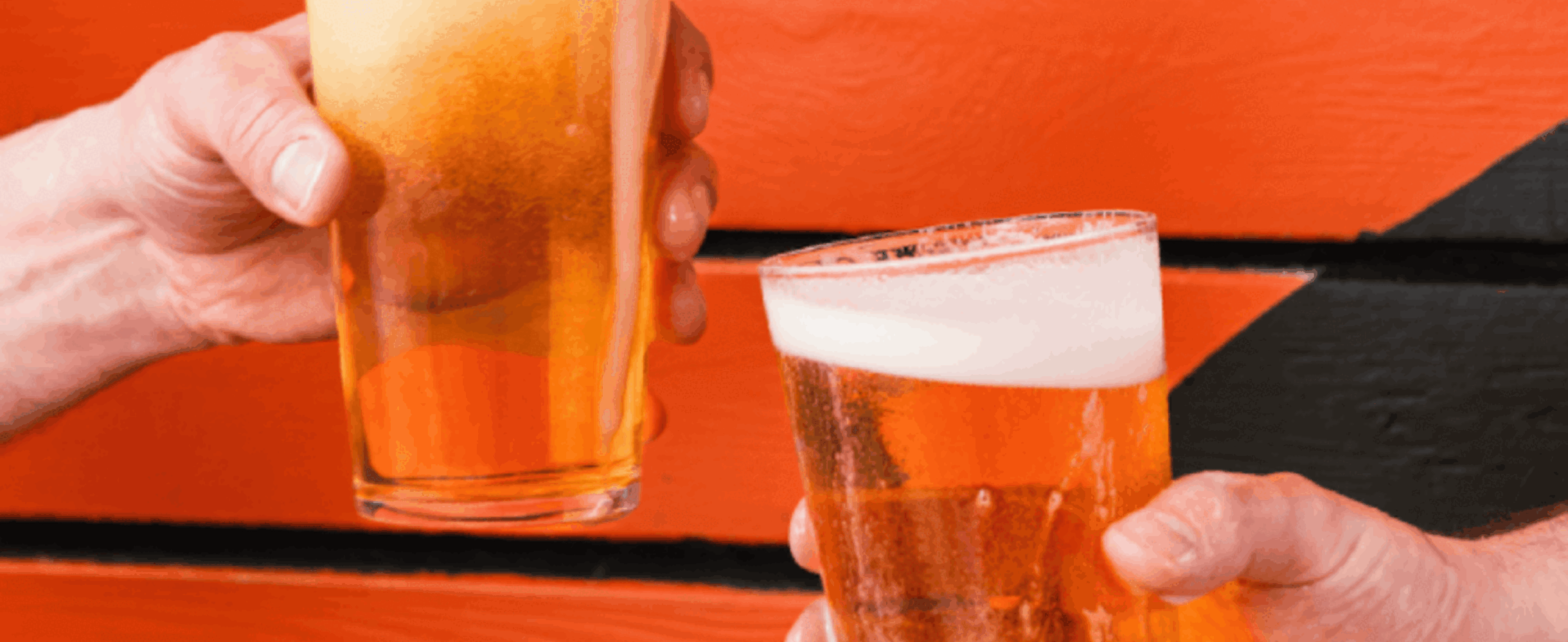 Two hands holding beer against an orange background