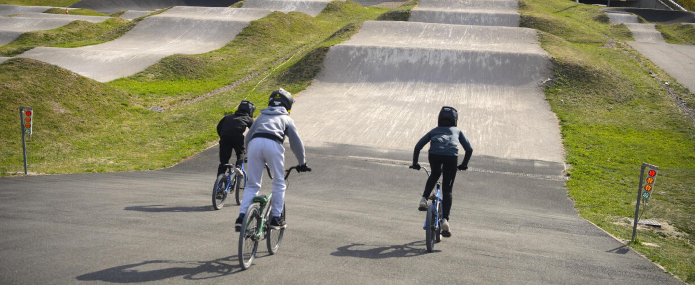 Three people cycle down the BMX track at Lee valley velopark