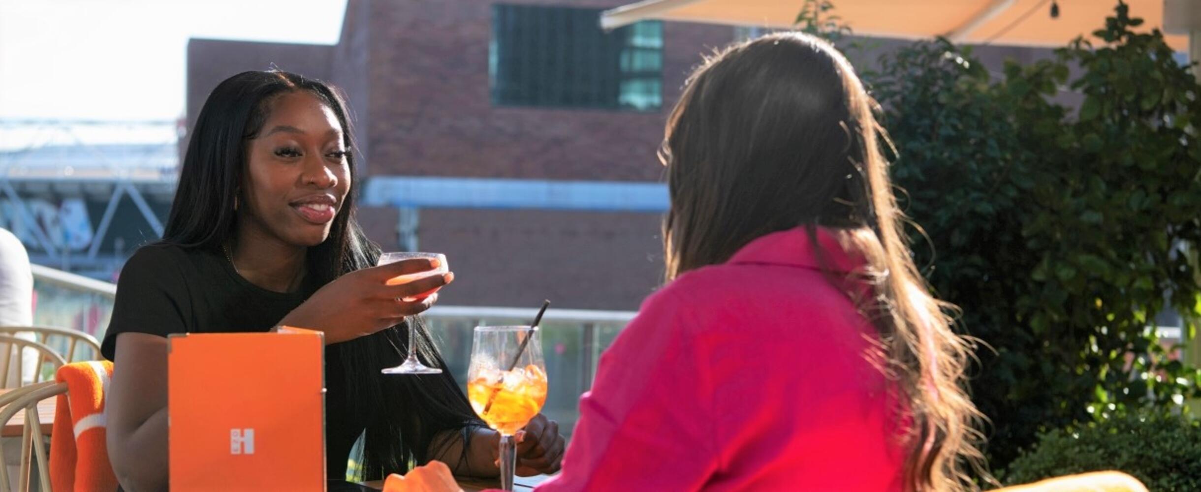 Two women sit on the Haugen rooftop bar with cocktails