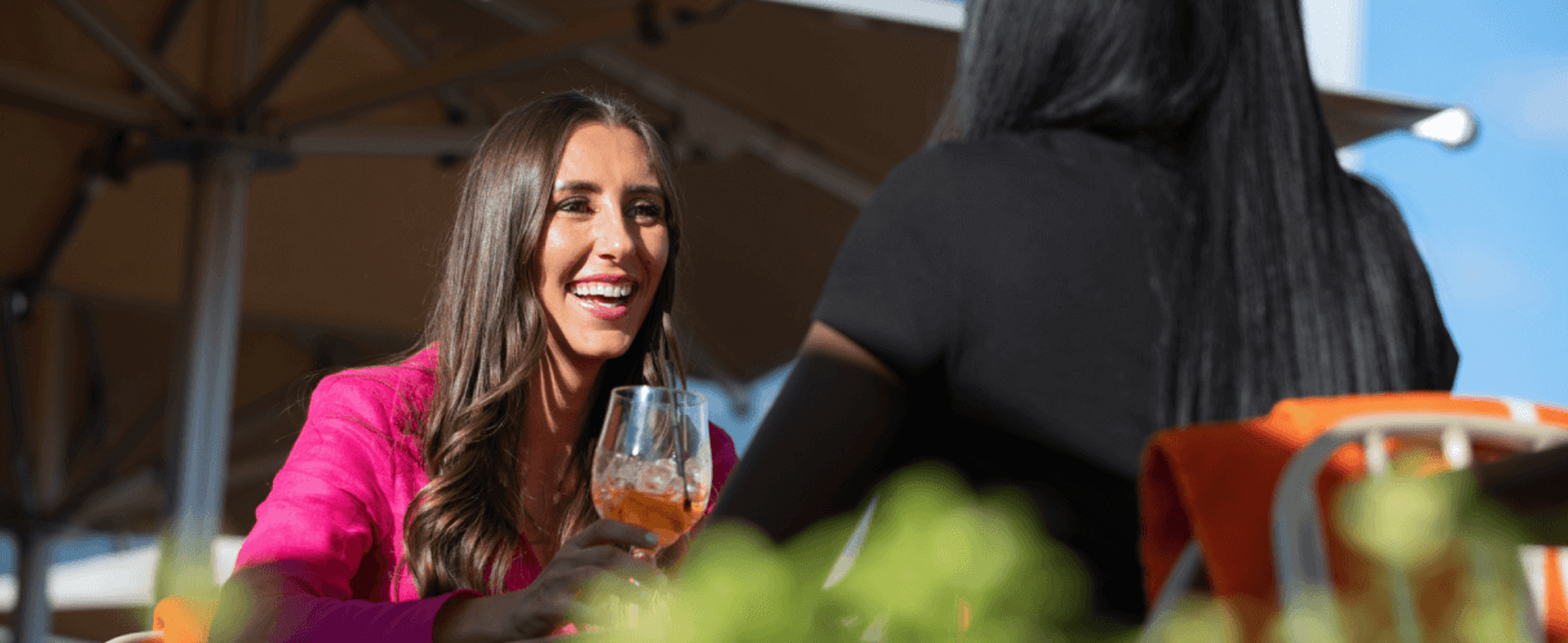 Two women enjoying cocktails on a rooftop