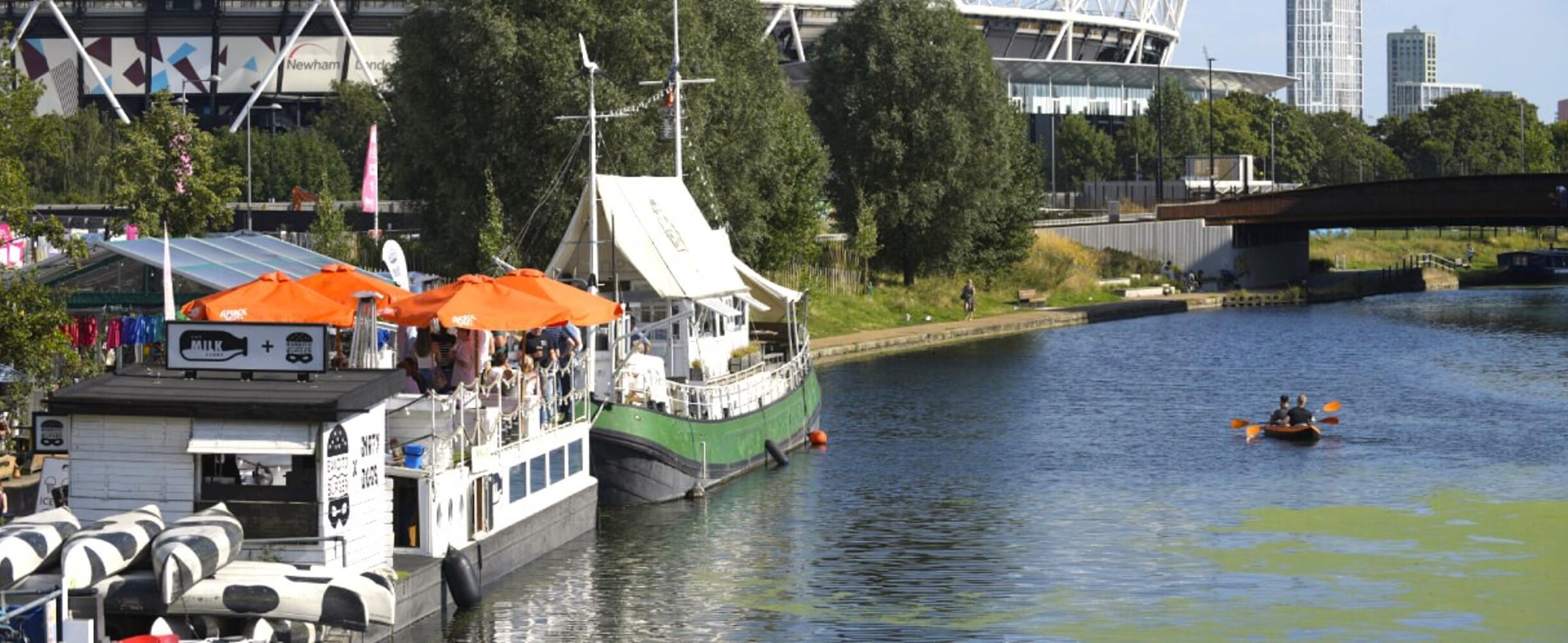 a canoe travels downriver next to Barge East