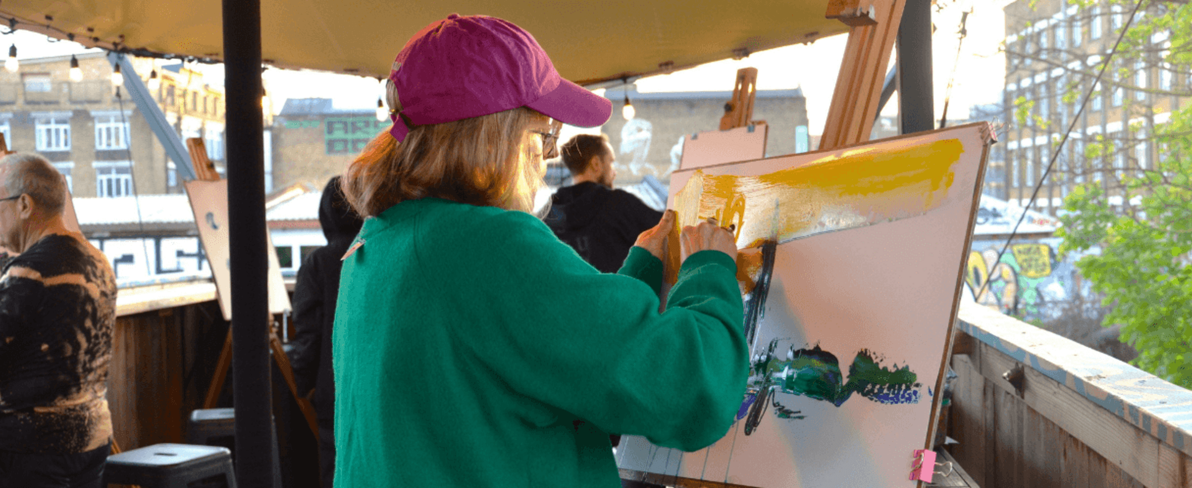 A woman in a pink cap painting a white canvas