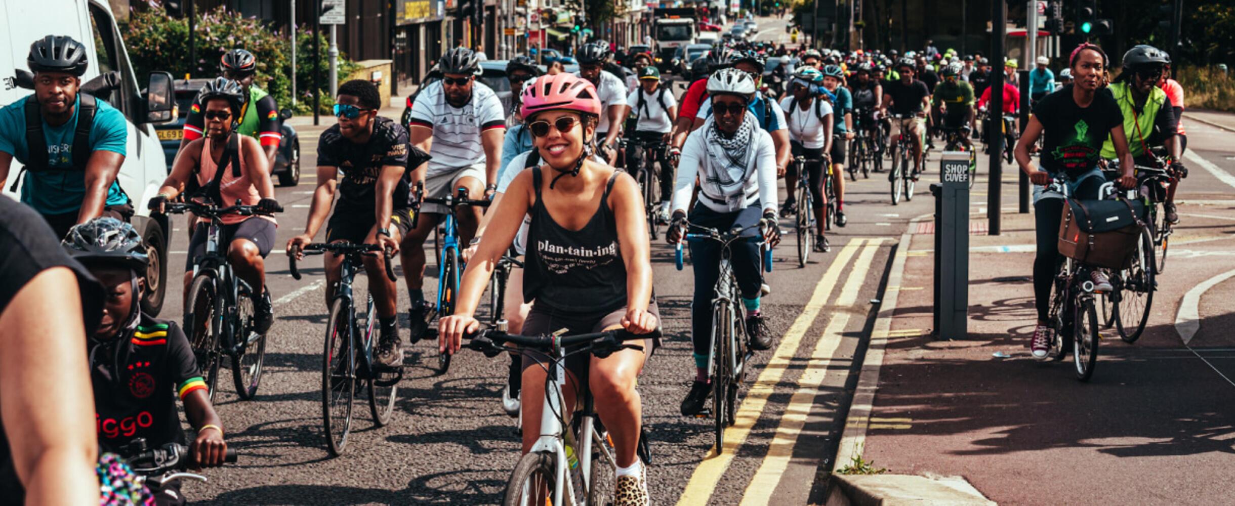 A group of Black cyclists ride along a road