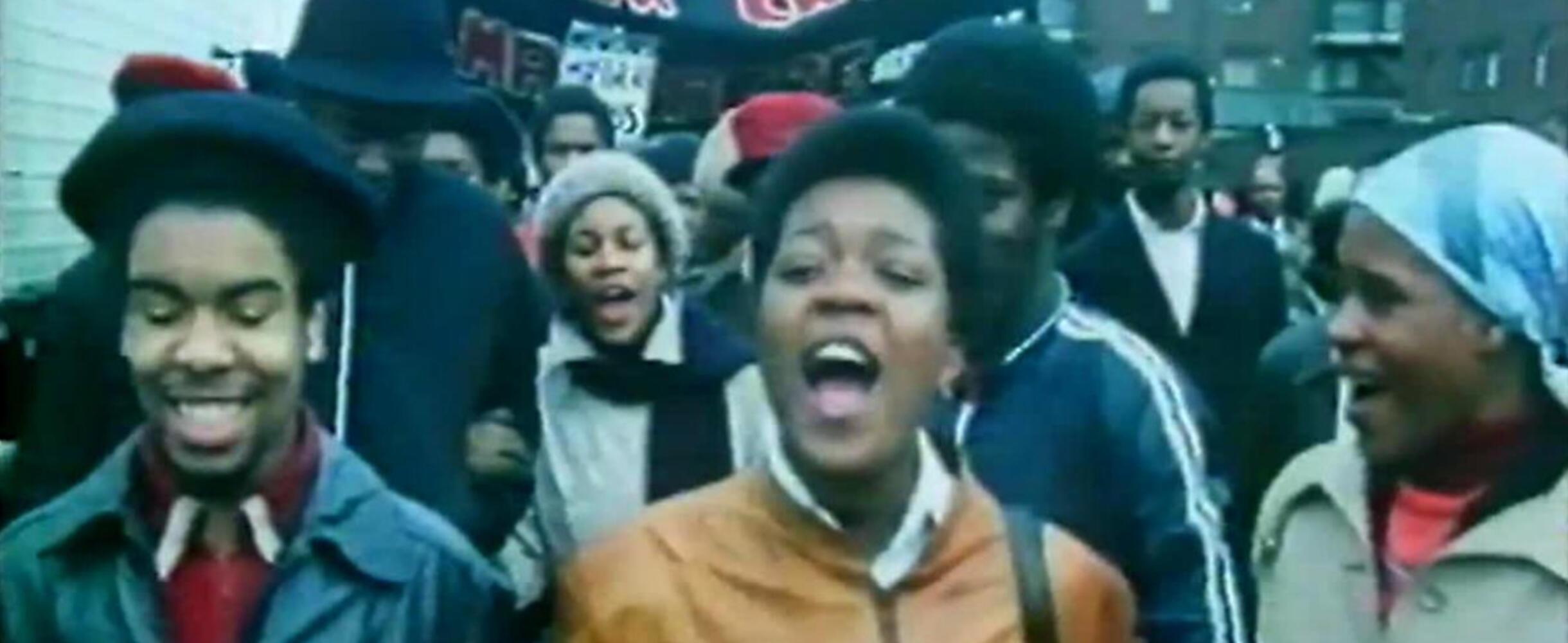 A group of people on a march shout and smile