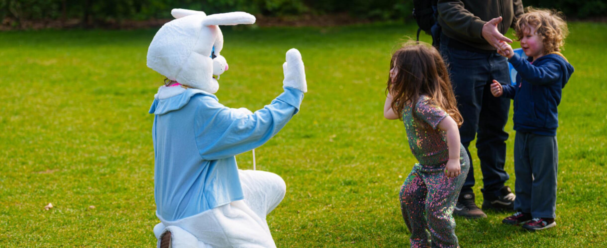 a large easter bunny high fives a child