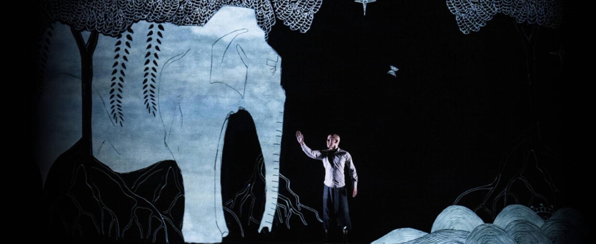 A man stands on a stage with a elephant-design behind him