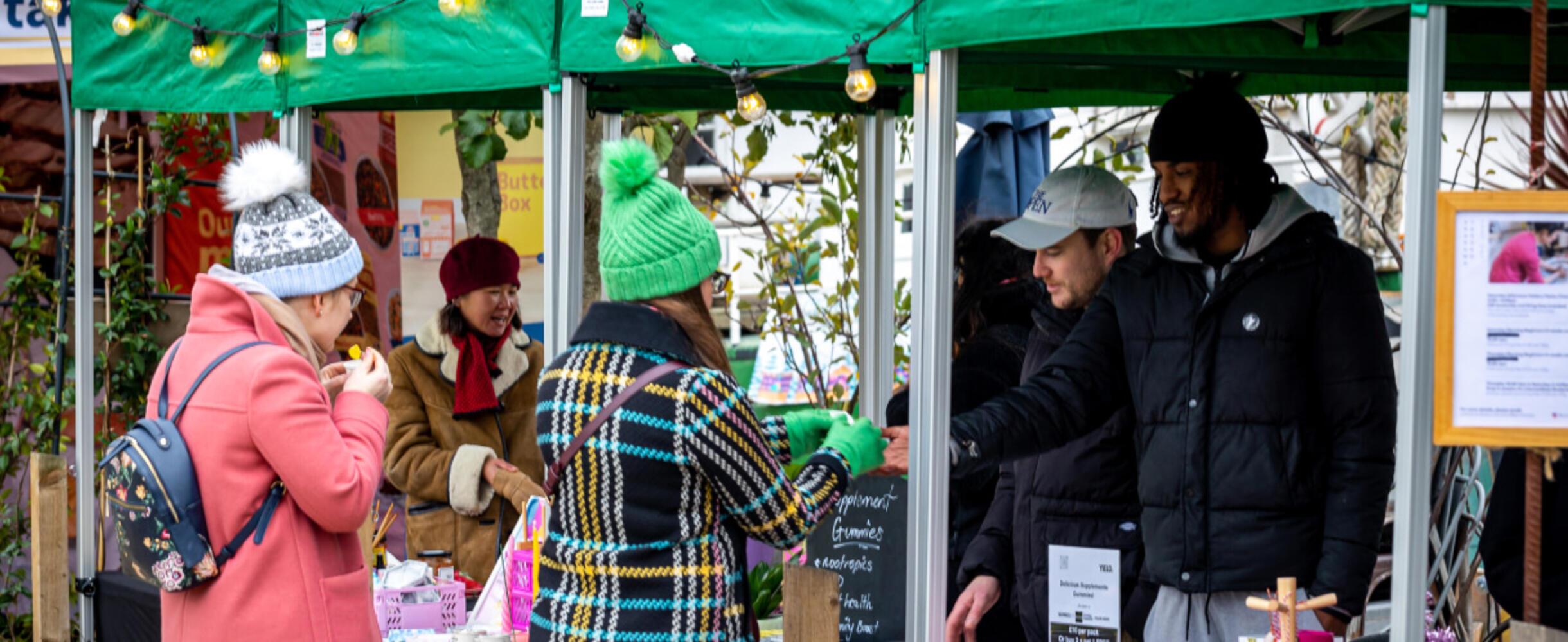 A Christmas market at Barge East with two people buying from a stall