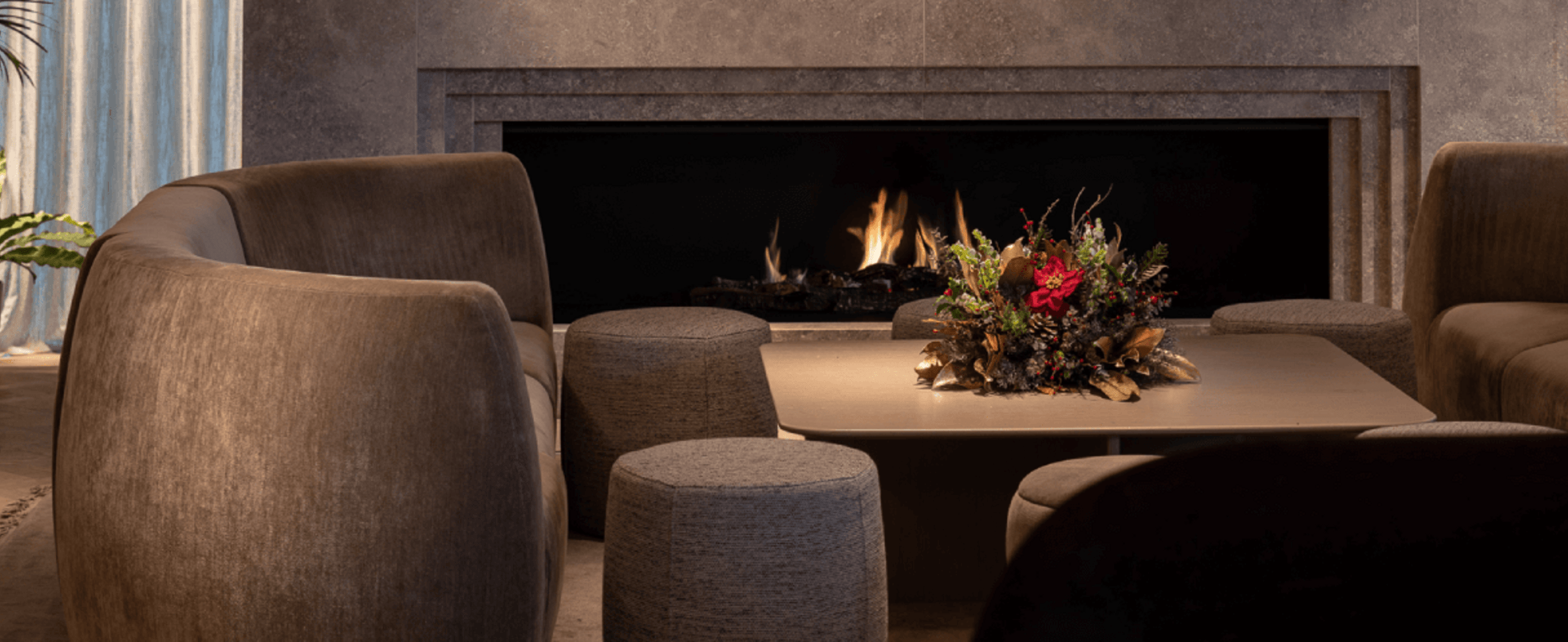 A room with a fire burning and a christmas wreath on a table