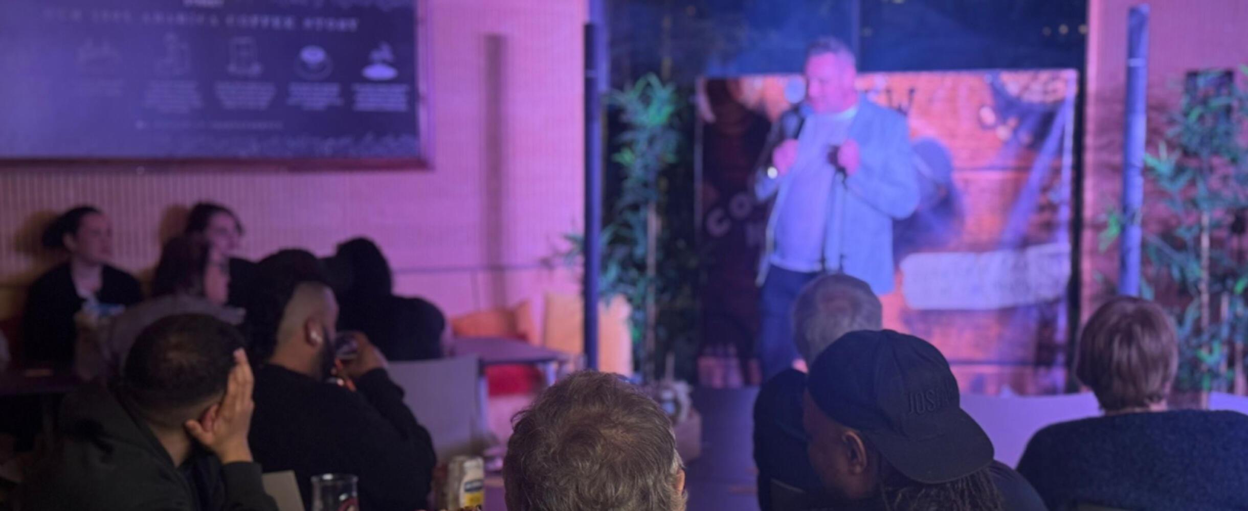 A man on stage at a comedy night
