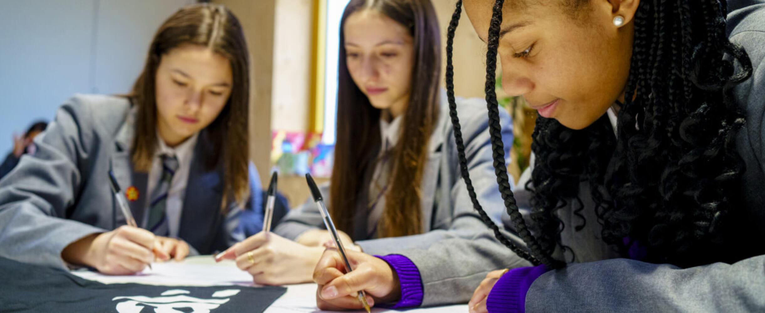 Three students at East Summer school fill out forms