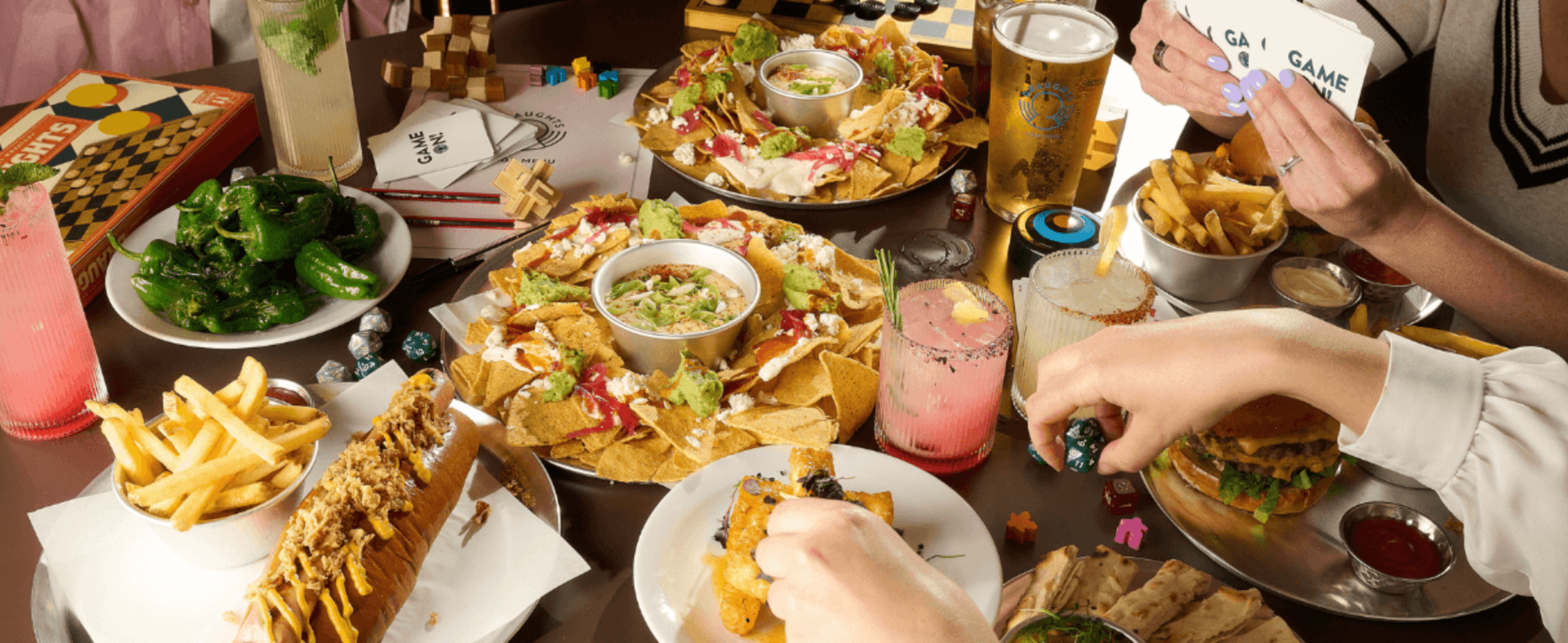 A circle of hands reach out for food on a table.