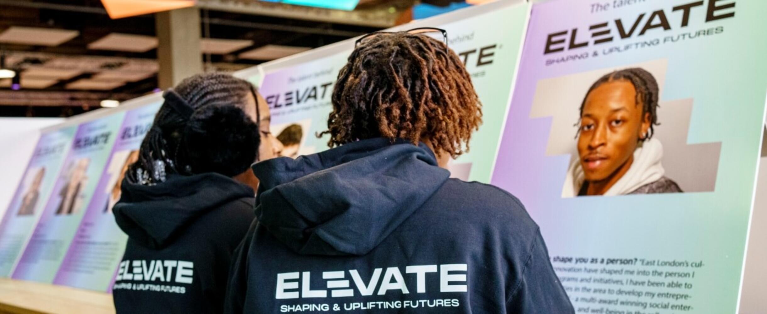 Two teenagers looking at nominee profiles at Elevate