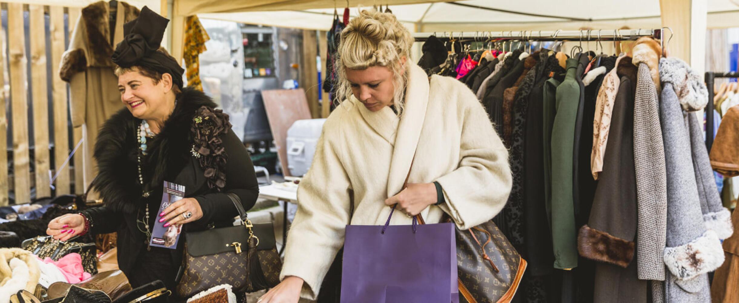 Two people shopping at a vintage stall at a market