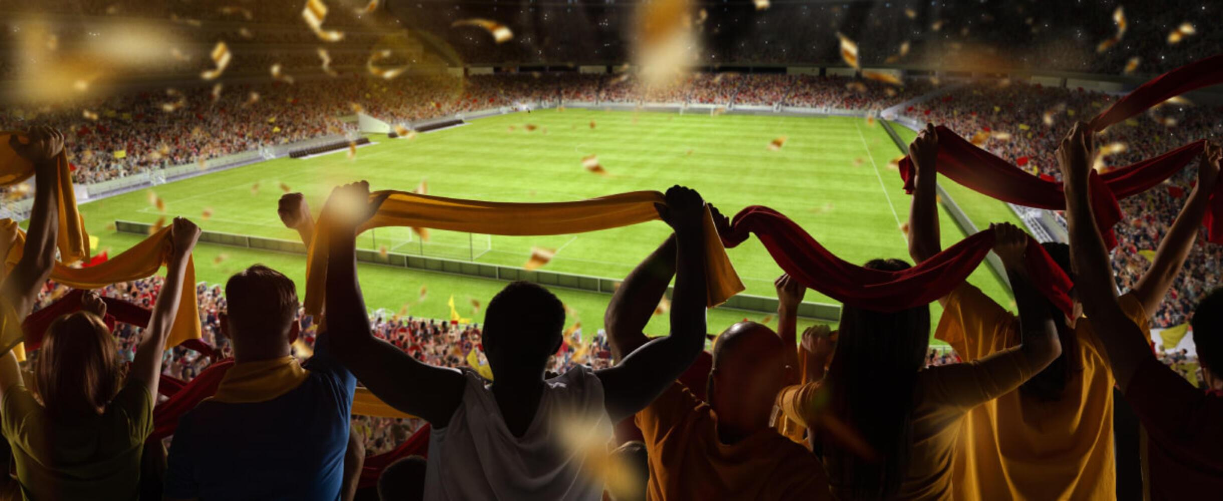 A crowd of fans hold up scarves at a football match