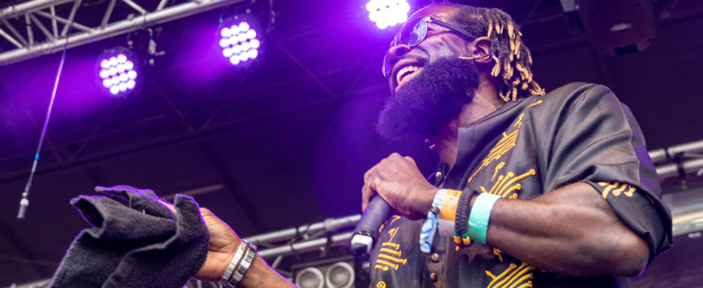 A musician on stage laughing and holding a microphone