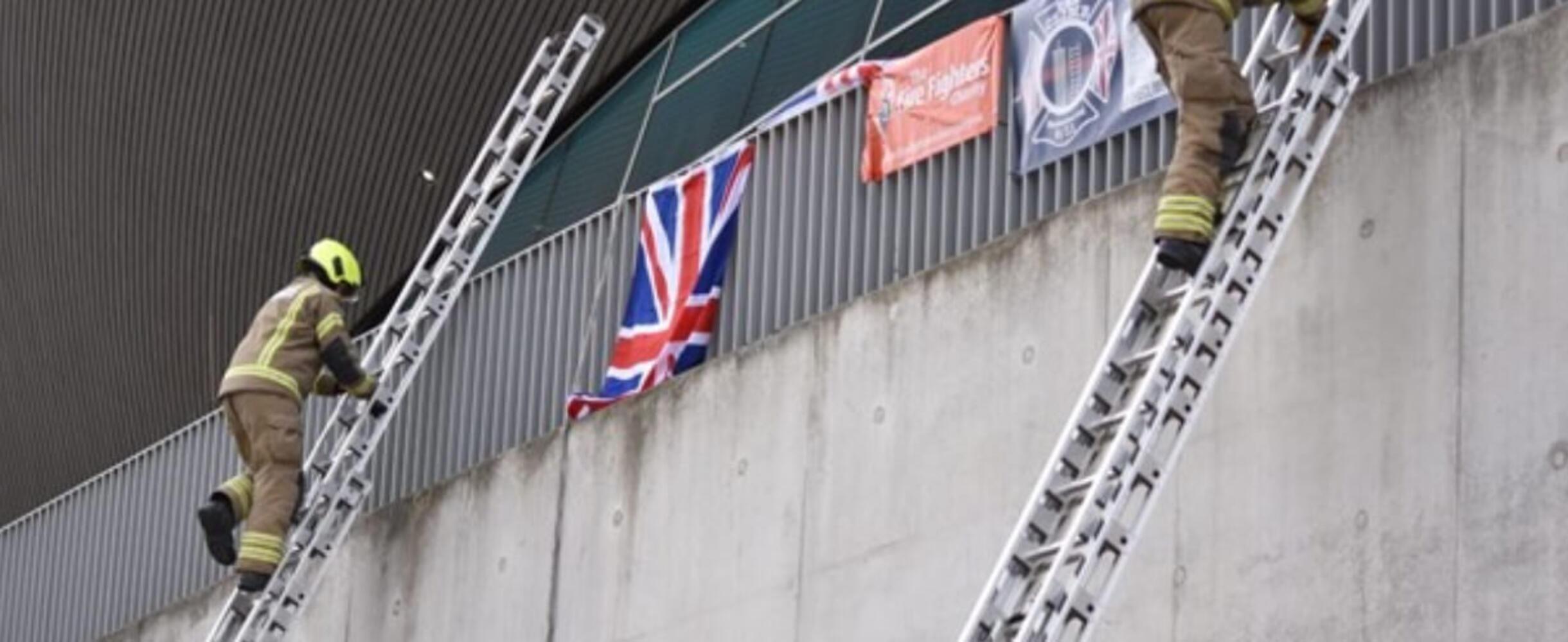 Two firefighters in full gear climb up ladders