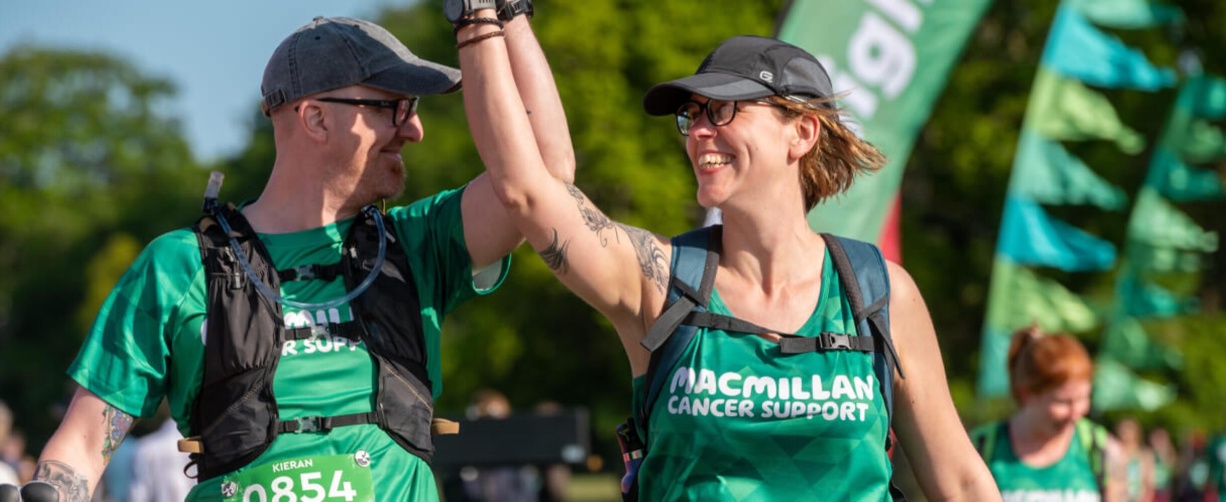 Two people hold hands and celebrate finishing the Macmillan Mighty Hike