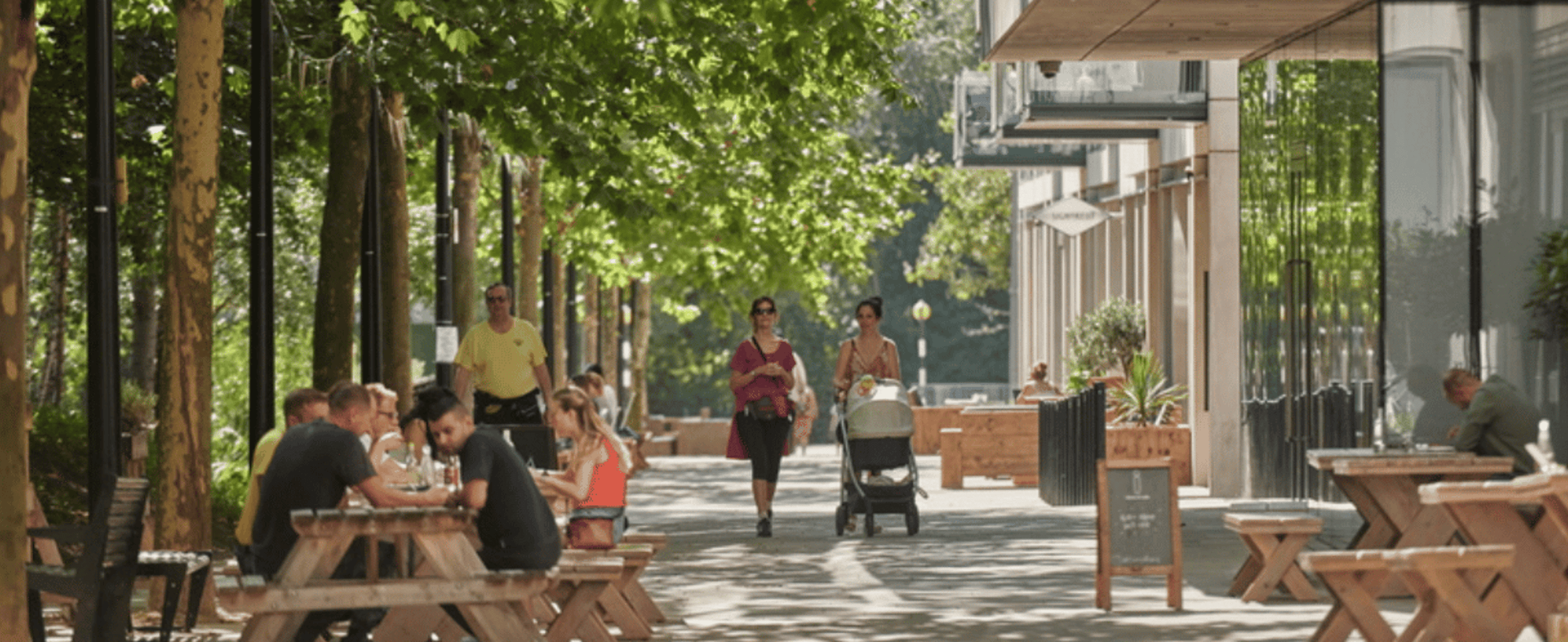 People dining and women with buggy walking on Queen Elizabeth Olympic Park