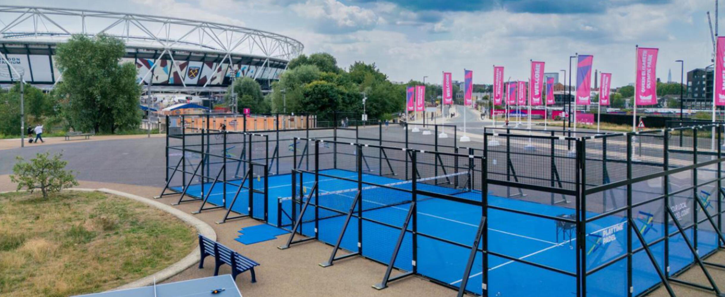 A blue padel court with a stadium in the background