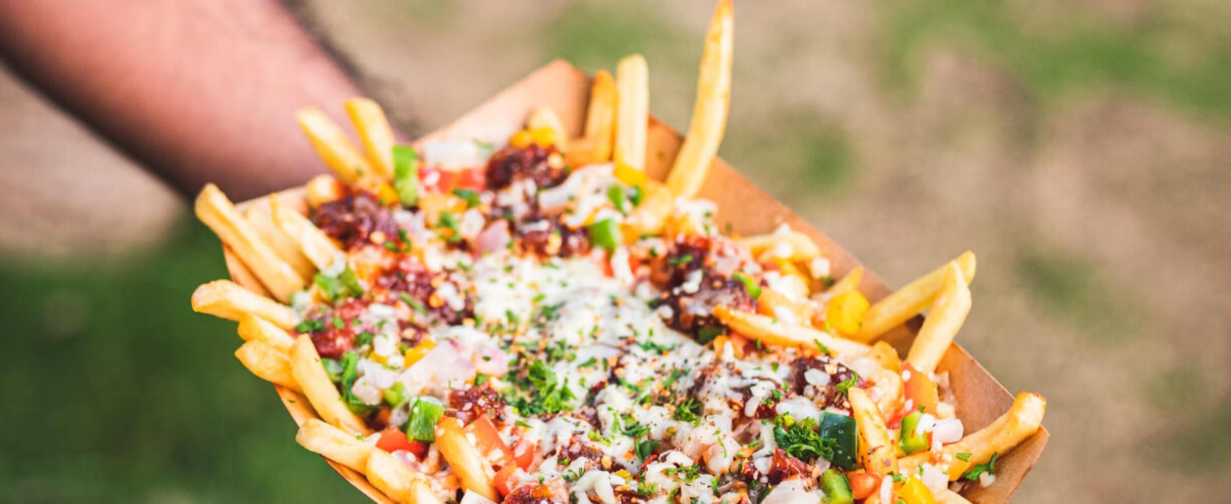 Someone holding a box of loaded fries.