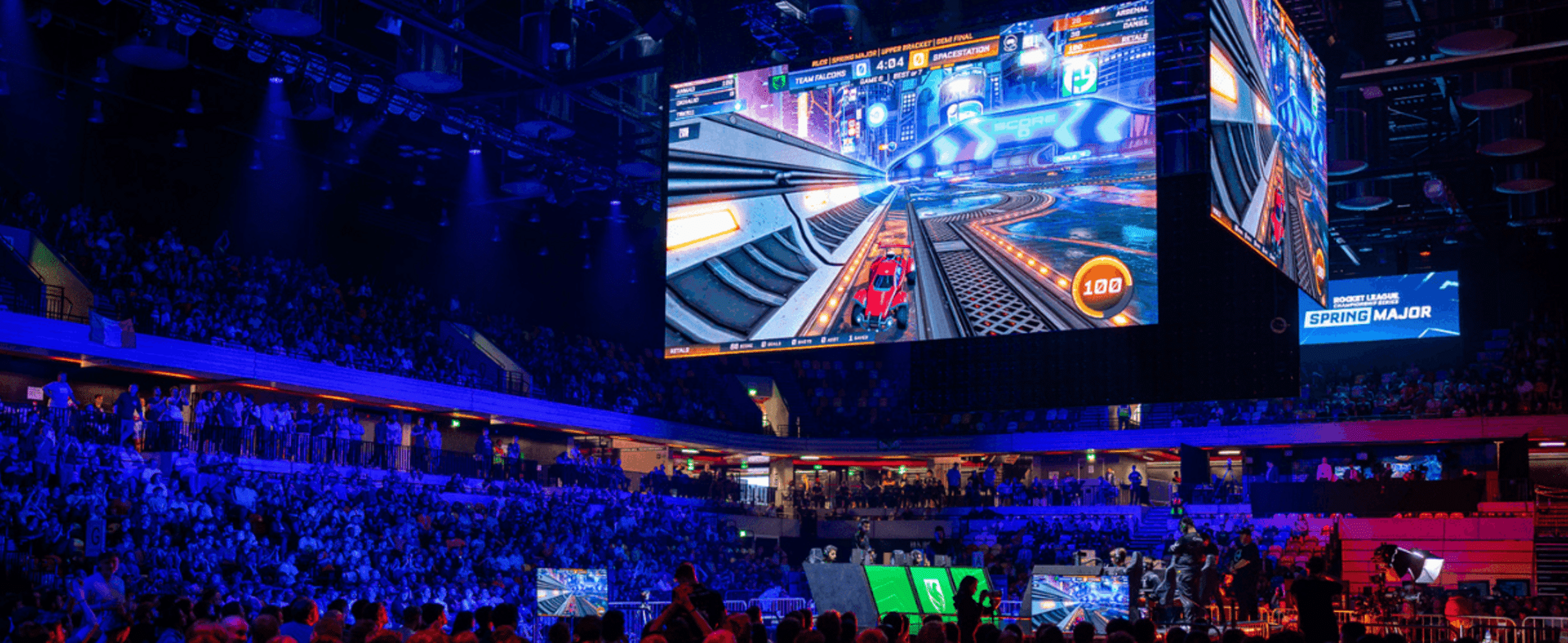 A large screen shows rocket league being payed in front of a crowd