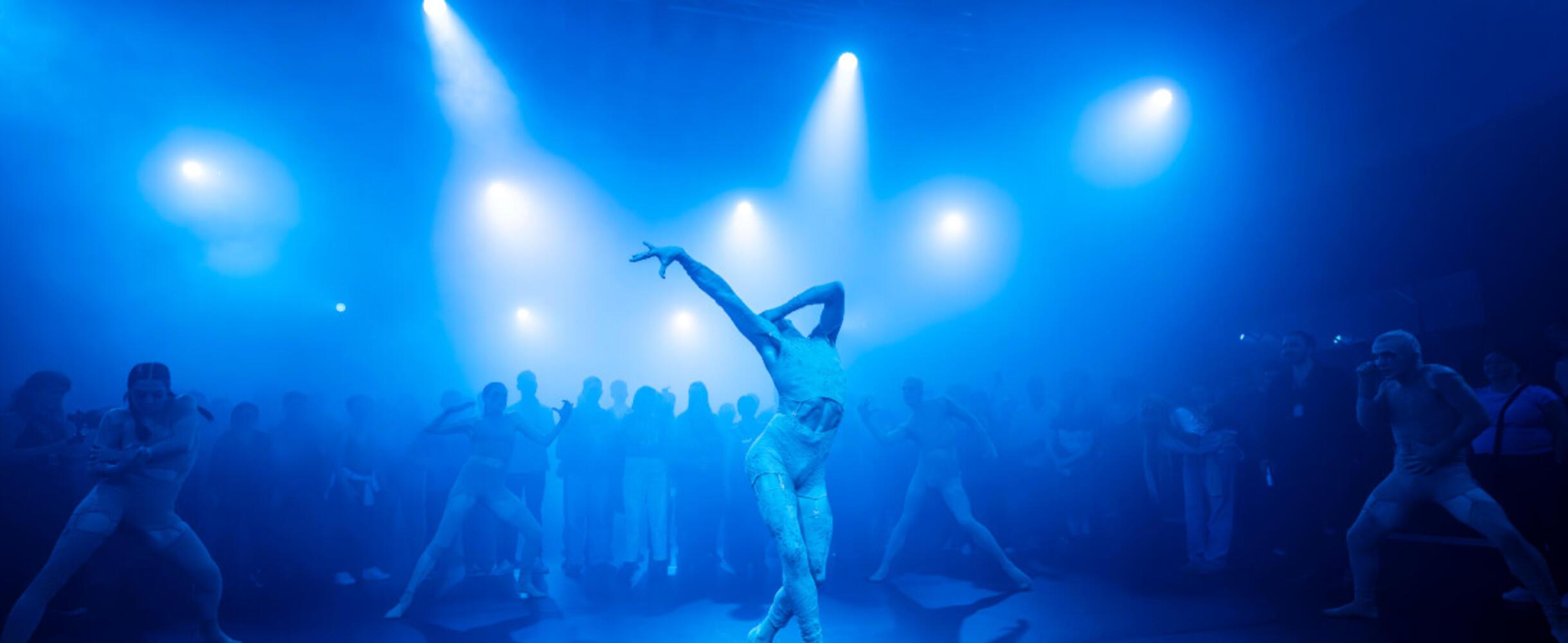 A group of dancers performing in blue light
