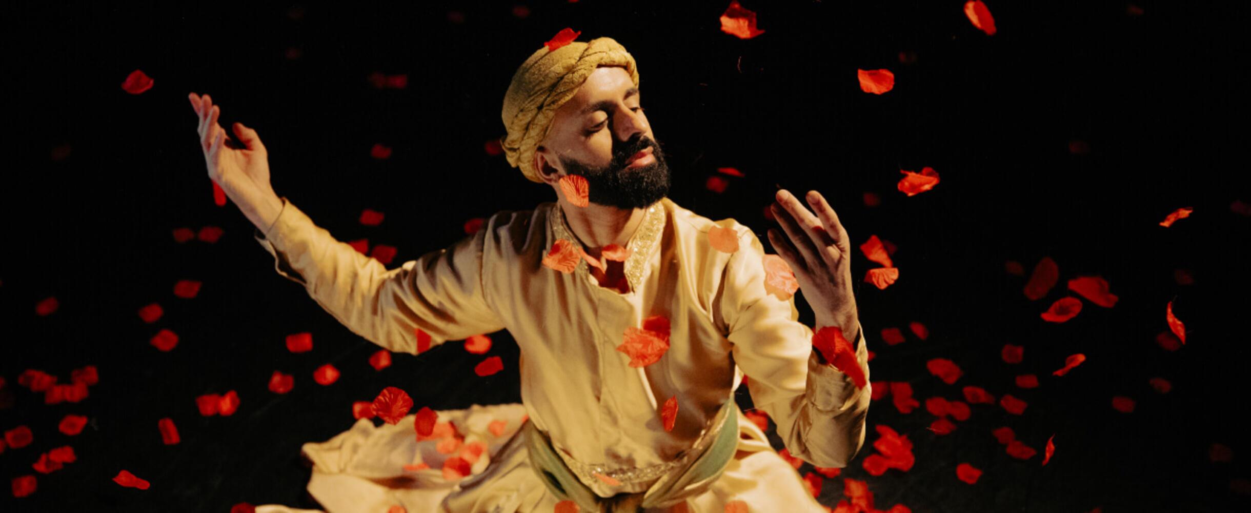 A man in a turban dancing amongst falling petals