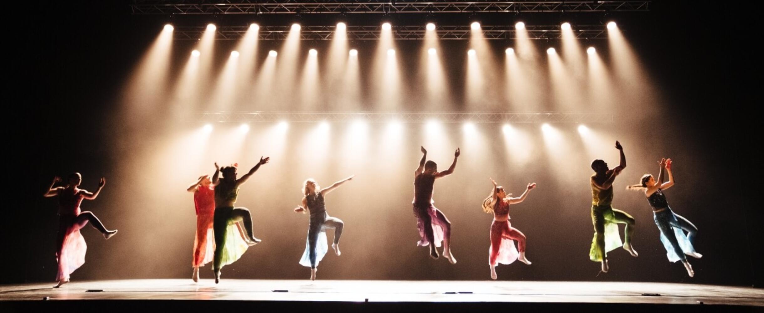 A group of dancers performing on stage with lots of overhead lights
