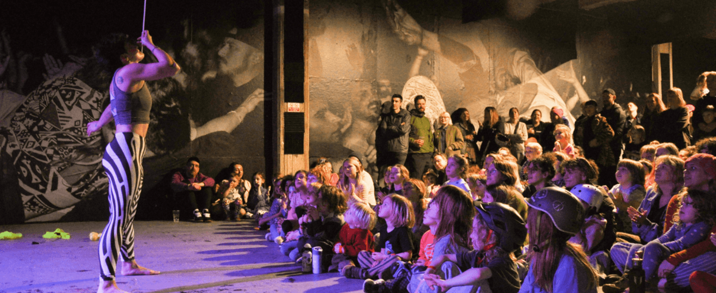 A performer singing in front of a crowd of children