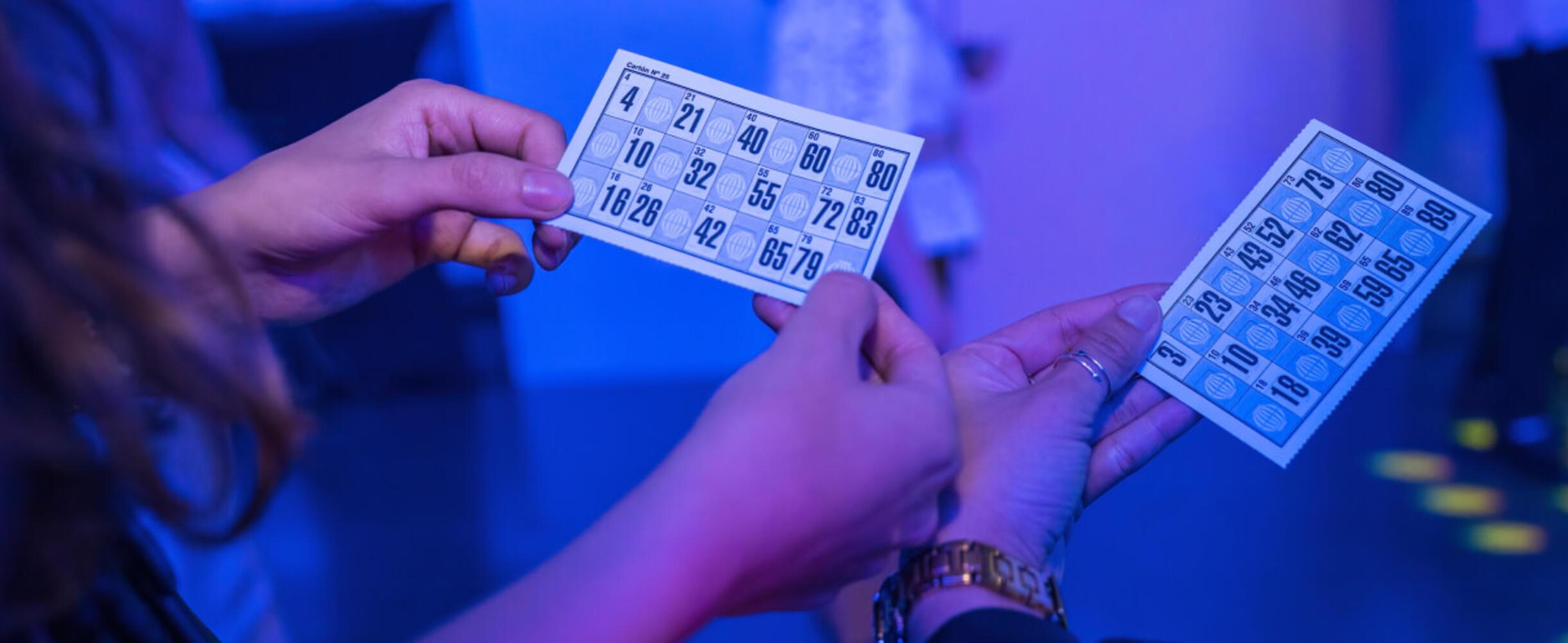Two people hold up bingo cards
