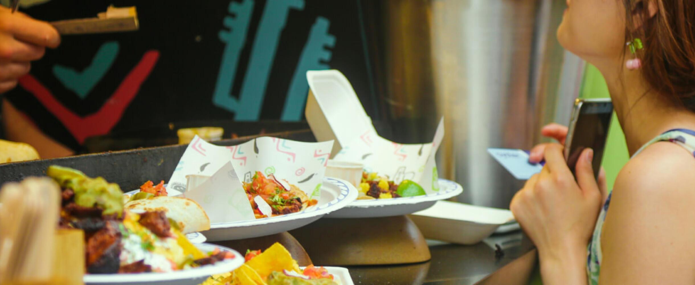 A person stands at the hatch of a street food van with food on the counter