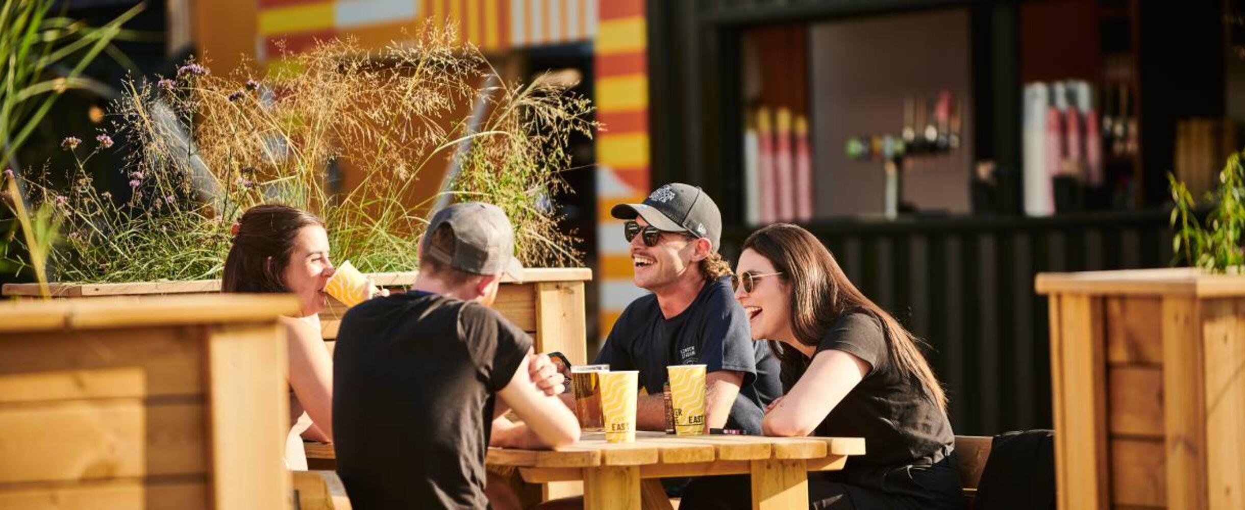 People laughing and drinking at Riverside East on Queen Elizabeth Olympic Park