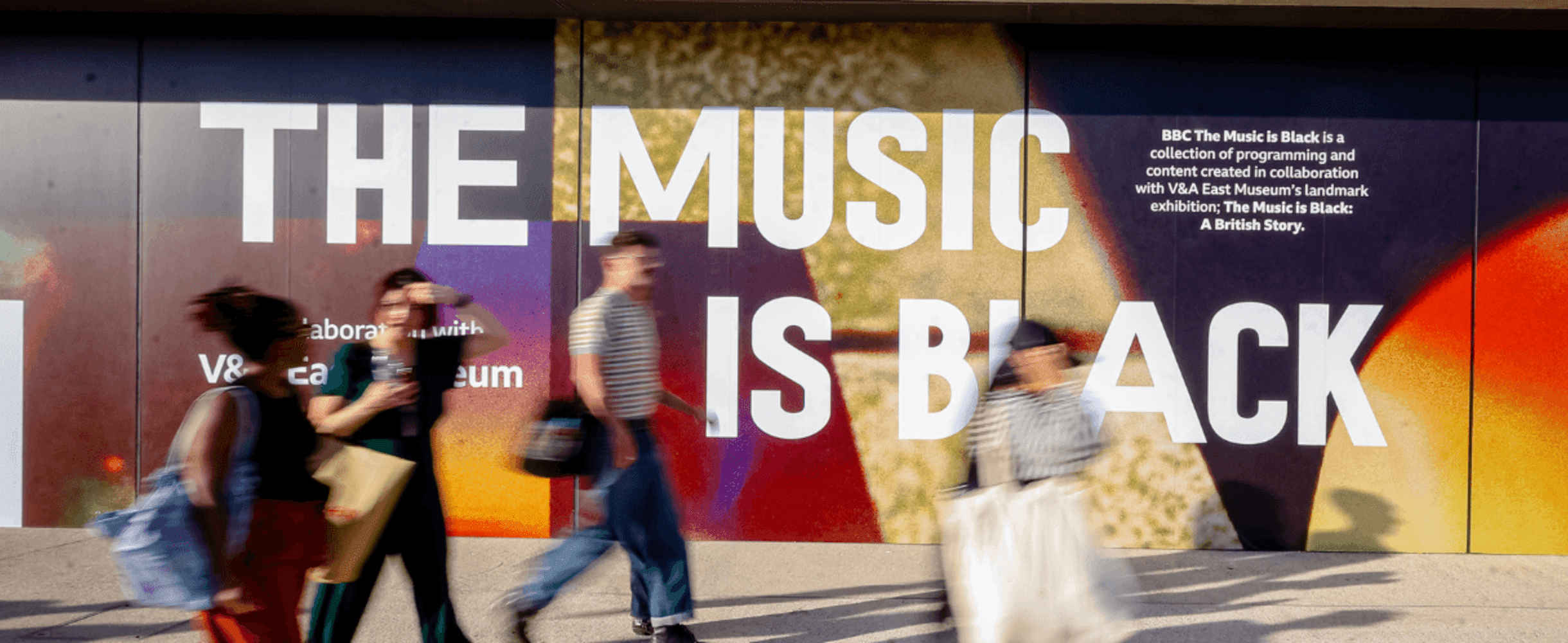 People walking in front of The Music is Black signage