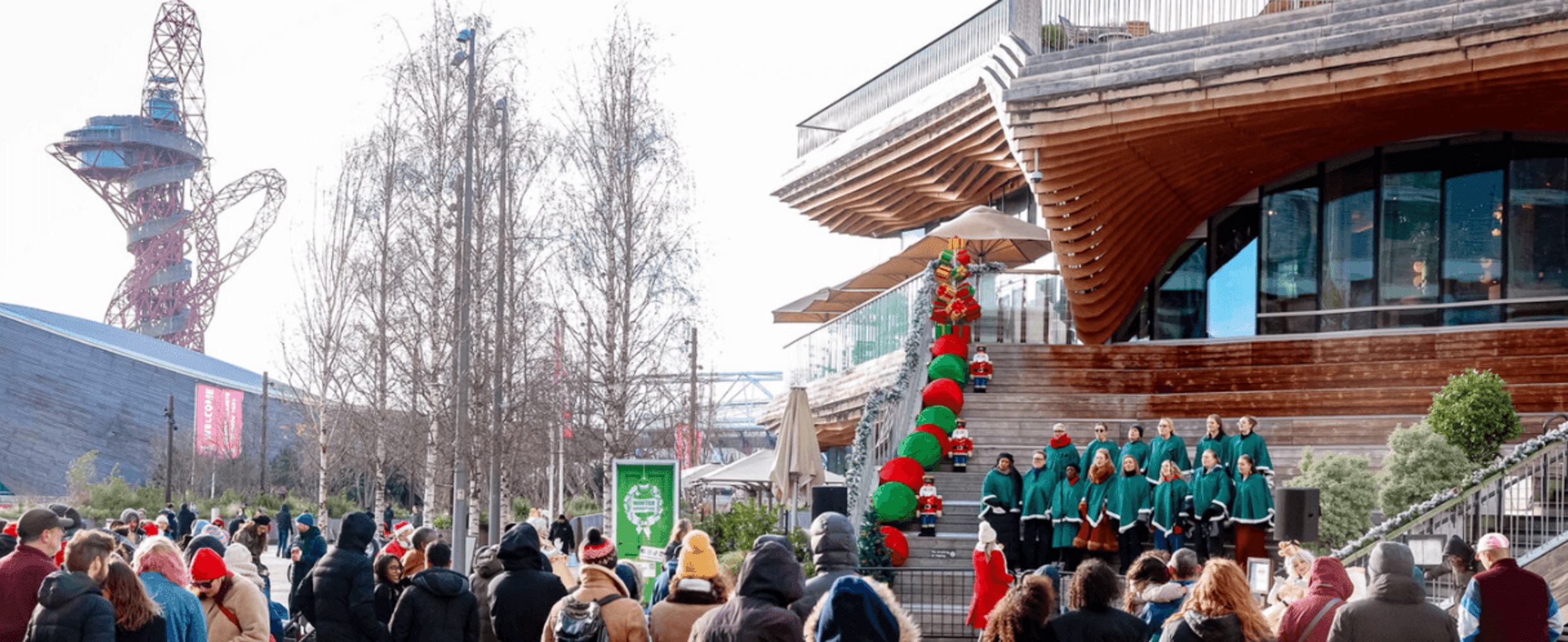A choir performing for a crowd with the ArcelorMittal Orbit in the background