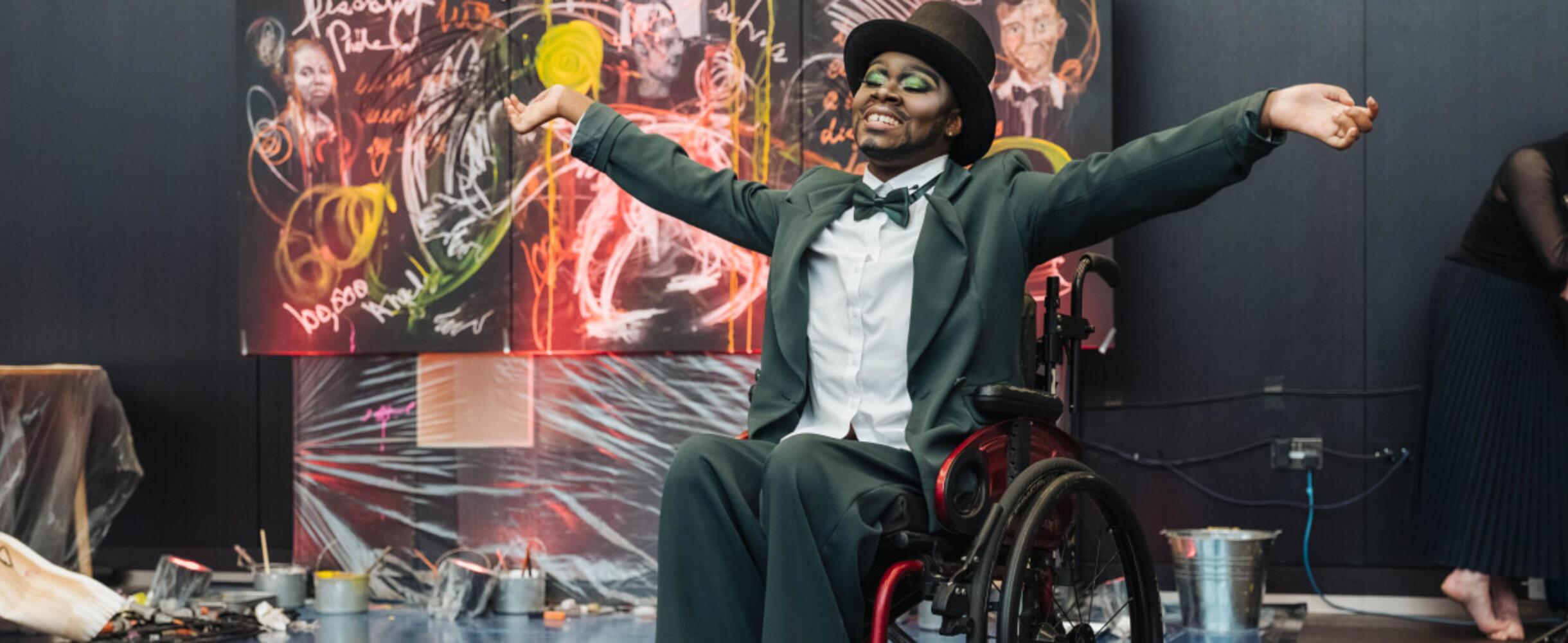 A person in a wheelchair celebrates in front of a painting