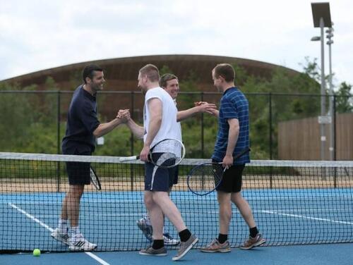 Four men shaking hands after competing in a doubles Tennis match