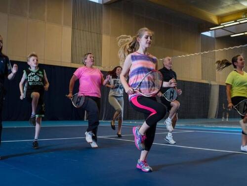 Young adults participating in an indoor Tennis class