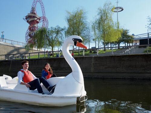 Two people laughing on swan shaped pedalo