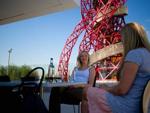 Two women talking on the Podium roof deck with the ArcelorMittal Orbit in the background